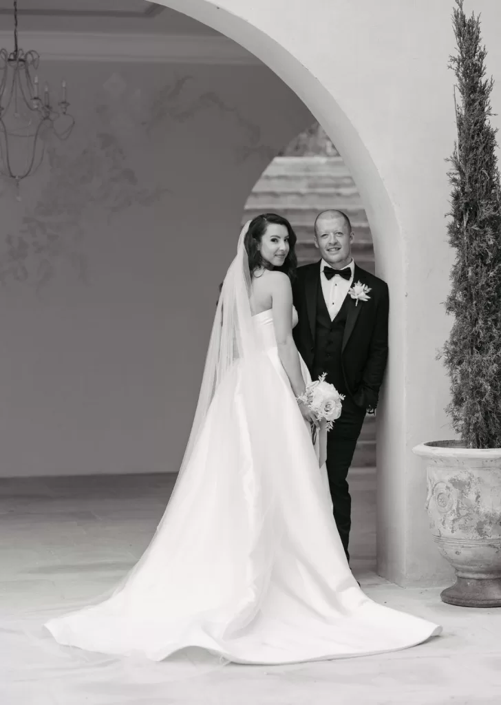 Black and white portrait of bride and groom framed by arch at Mas Torroella