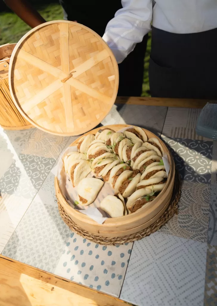 Steamed bao buns filled with pulled meat, presented in a woven bamboo steamer at Mas Torroella.
