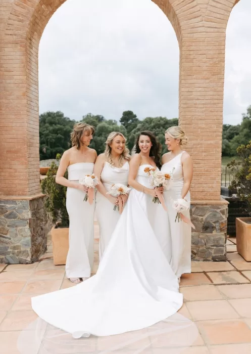 Bride laughing with bridesmaids under terracotta arch at Mas Torroella