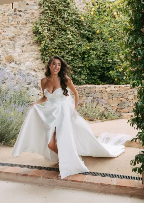 Candid moment of bride laughing with bouquet in hand in Mas Torroella’s lush garden