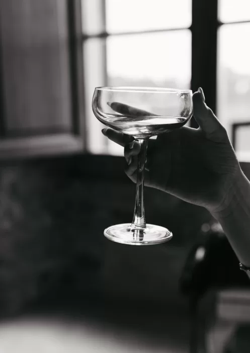 Woman holding an elegant coupe glass in soft black and white light at Mas Torroella.