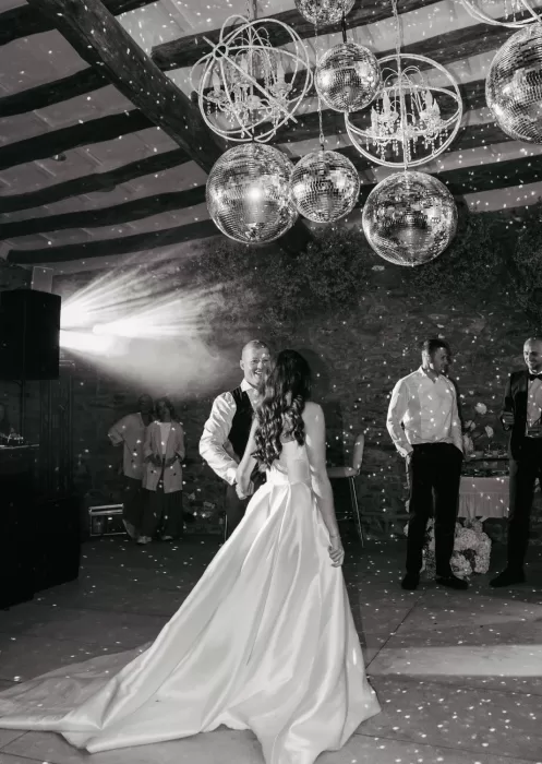 Bride and groom dancing under sparkling disco balls at Mas Torroella during their first dance, with dramatic lighting and joyful energy.