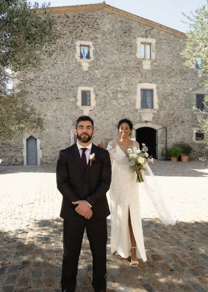 Bride approaching the groom for their first look outside the rustic stone façade of Mas Torroella.