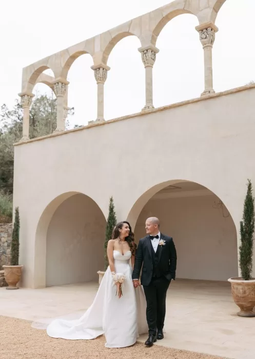 Newlyweds sharing a moment while walking outside Mas Torroella’s arched building