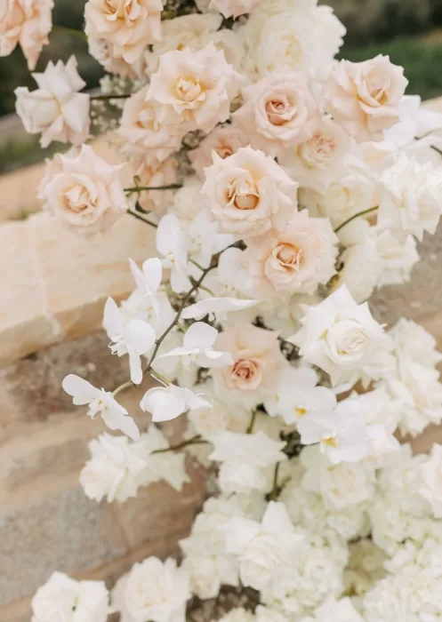 Close-up of blush roses and white orchids in wedding ceremony flowers at Mas Torroella