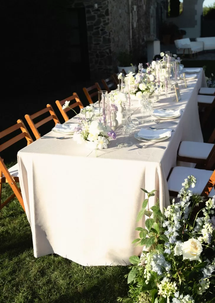 Elegant floral arrangements and lilac taper candles on wedding table at Mas Torroella.