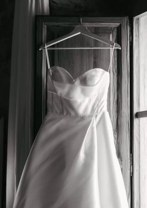 Strapless satin wedding dress hanging by wooden shutters at Mas Torroella