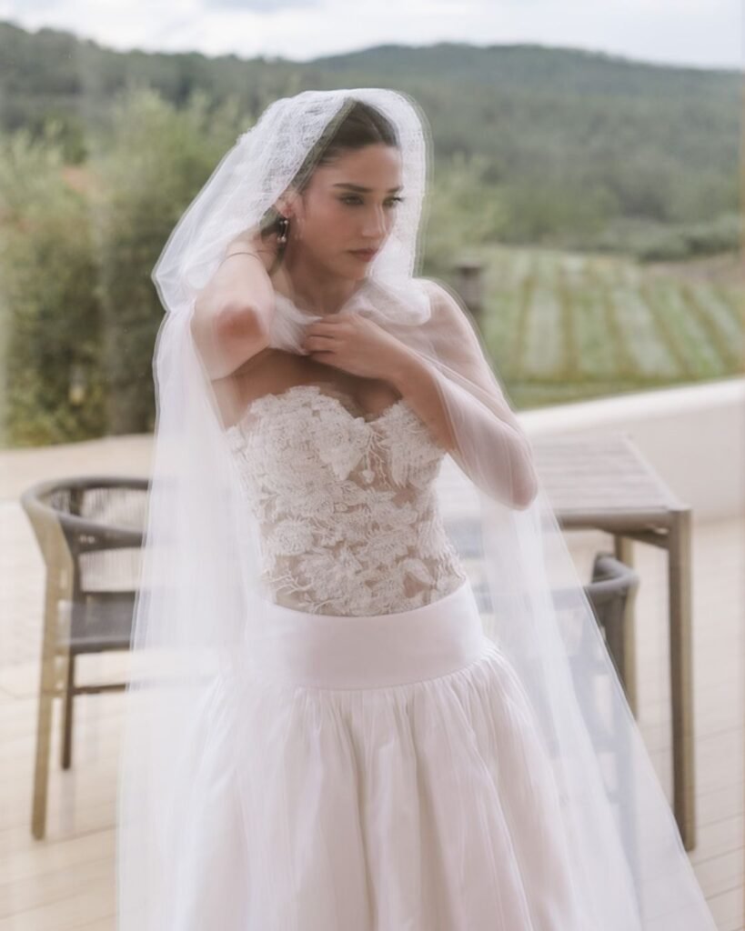 Soft portrait of bride adjusting her veil, set against the serene backdrop of Masia Cabellut's vineyard landscape.