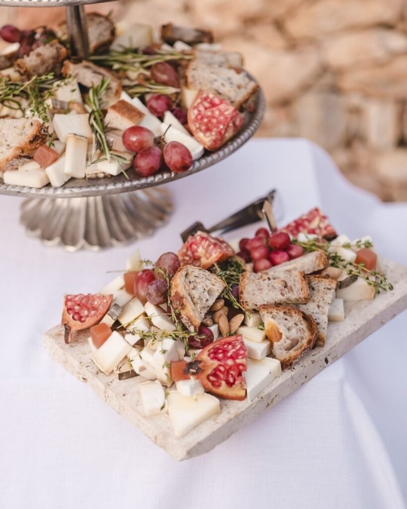 Rustic cheese board with pomegranate, grapes, and artisan bread at Masia Cabellut wedding reception.