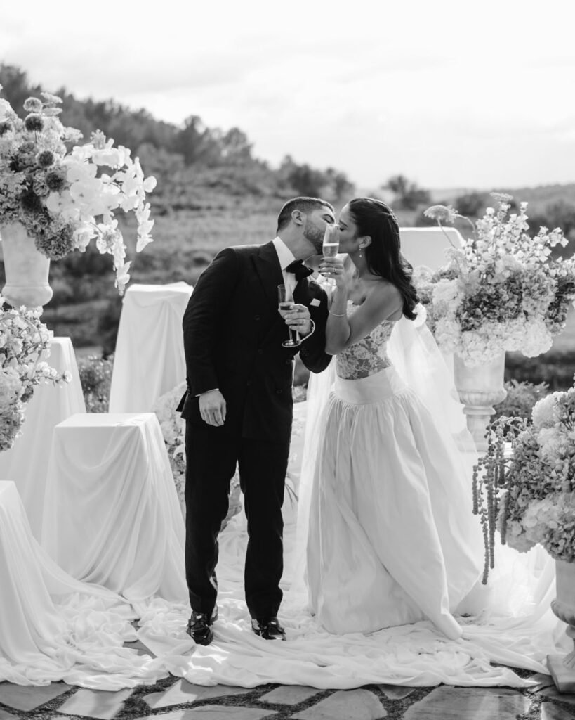 Romantic black-and-white portrait of newlywed couple sharing a celebratory champagne toast at Masia Cabellut wedding.