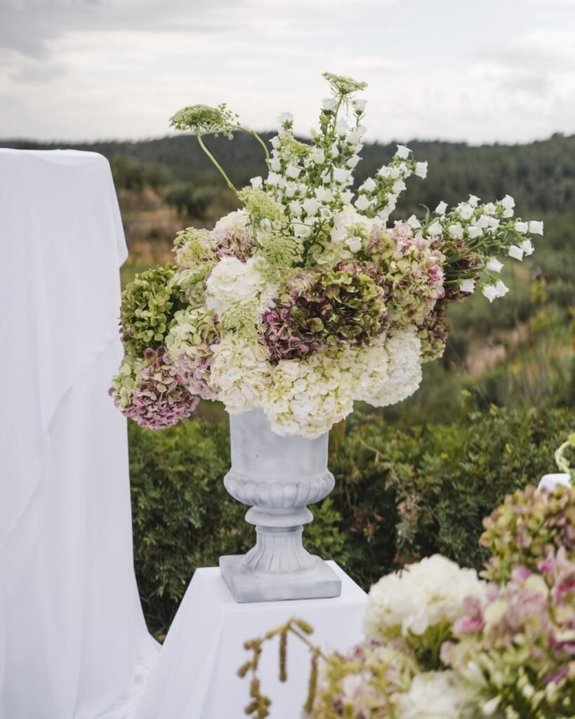 Elegant wedding floral centerpiece displayed against the lush landscape backdrop of Masia Cabellut.