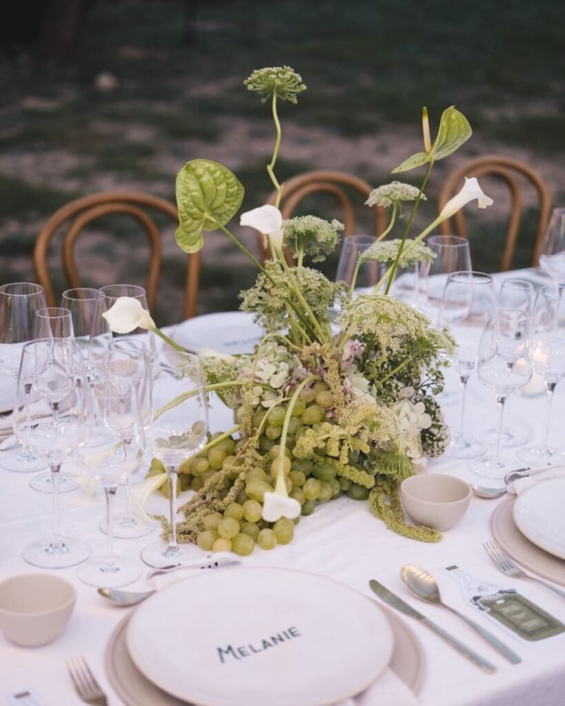 Lush green grape and floral centrepiece with white calla lilies at Masia Cabellut.