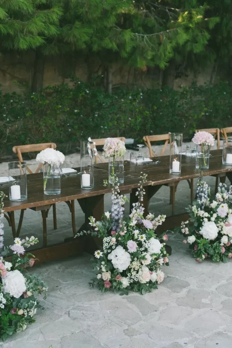 Rows of soft pastel flowers lining the rustic banquet tables at a Liopetro wedding reception.