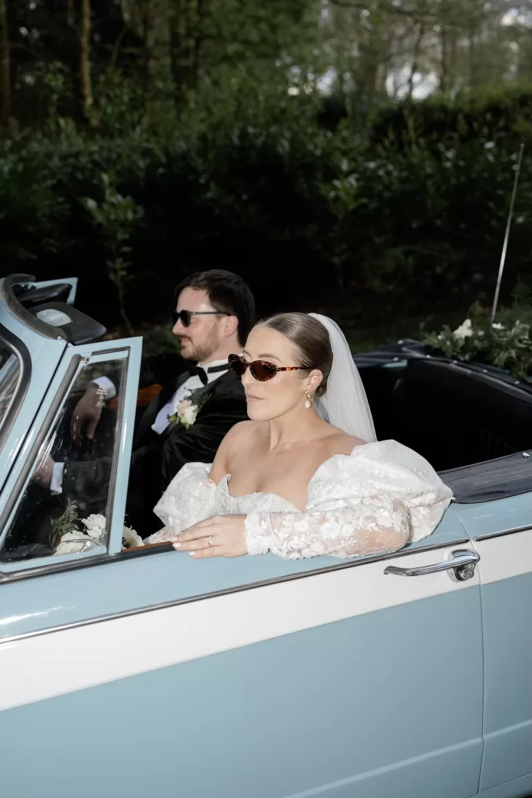 Bride and groom stylishly driving away in powder blue vintage convertible, photographed by Sharon Cudworth.