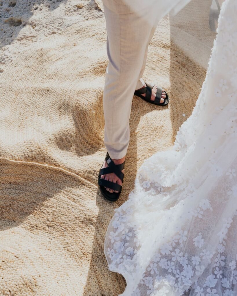 Close-up of the groom’s sandals and the bride’s floral train during a barefoot ceremony at Six Senses Ibiza.