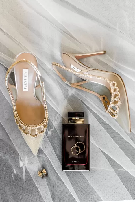 Bride’s elegant wedding heels and Dolce & Gabbana perfume styled on veil at Uzutrakio Dvaras.