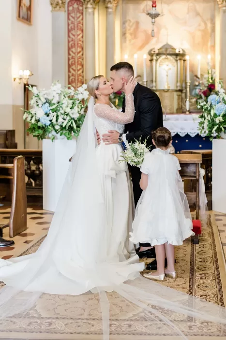 Bride and groom share a romantic kiss during their wedding ceremony at Uzutrakio Dvaras church.