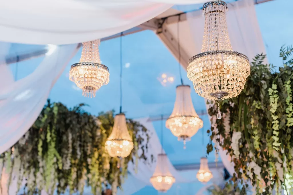Elegant crystal chandeliers and flowing white drapery at Uzutrakio Dvaras wedding reception.