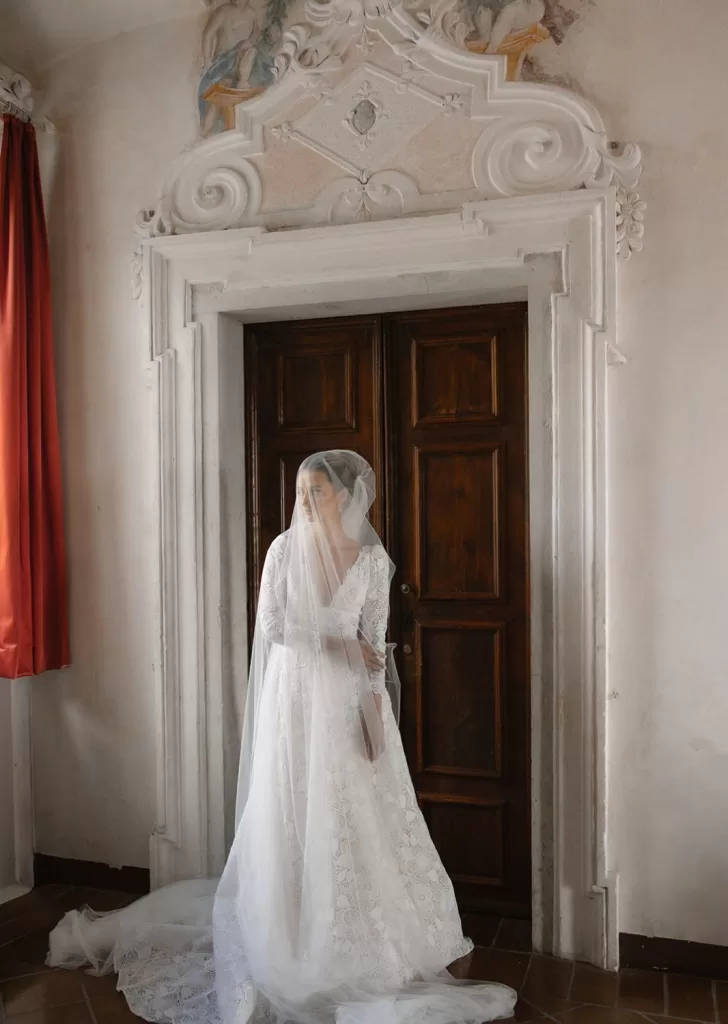 Bride in lace and tulle illuminated by warm natural light in a romantic corner of Villa Cariola.