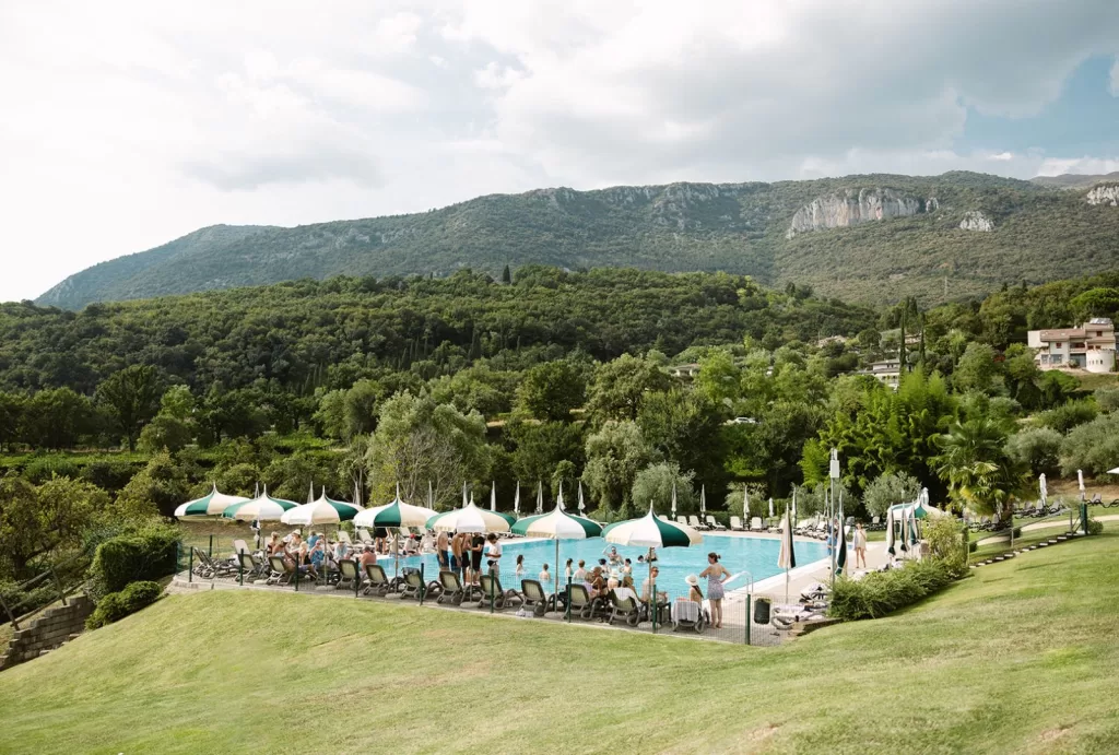 Lush green hills surround Villa Cariola’s poolside celebration area on a sunny day.