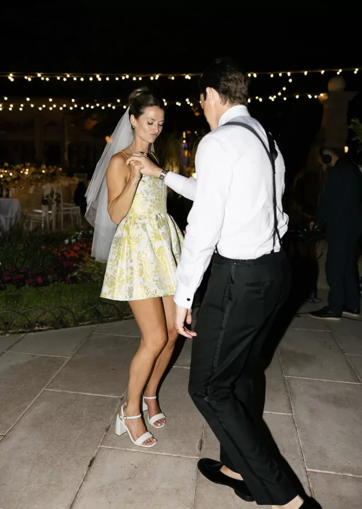 Bride and groom share a romantic dance under string lights at Villa Cariola.