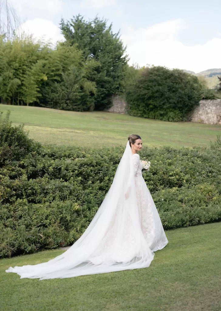 Bride walks through the gardens of Villa Cariolla, her long veil trailing over the manicured lawn.