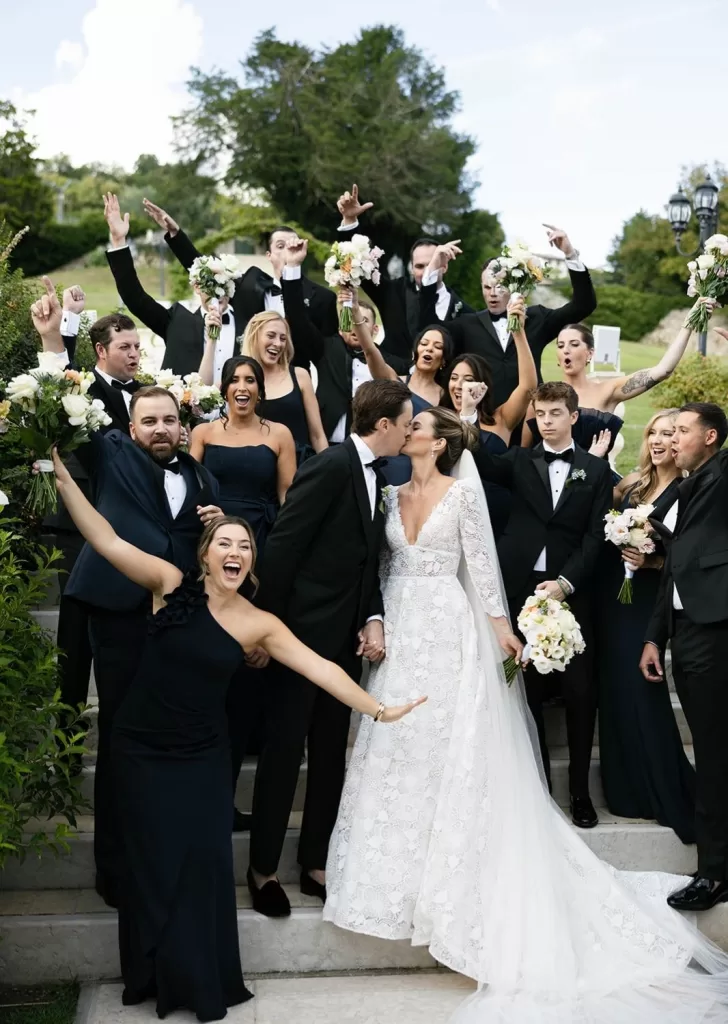 Bride and groom celebrating with their joyful wedding party on the stone steps of Villa Cariolla.