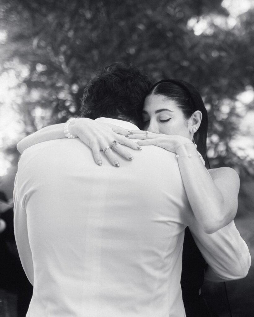 Intimate black and white moment as the bride holds her groom close during their first dance at Villa Ivana.