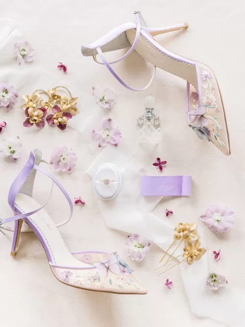 Bride’s accessories arranged artfully—pearl earrings, lace garter, and a vintage perfume bottle—on a marble table at Bastide du Roy.
