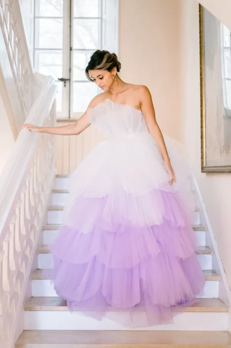 Bride standing at the top of the grand tulle-draped staircase at Bastide du Roy, looking into the sunlit courtyard.