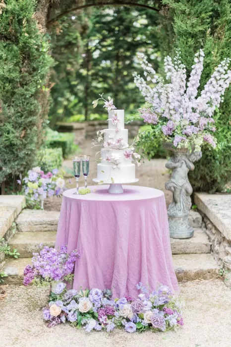 Wedding cake display at Bastide du Roy featuring rustic wooden crates, floral arrangements, and vintage cake stands in the garden.