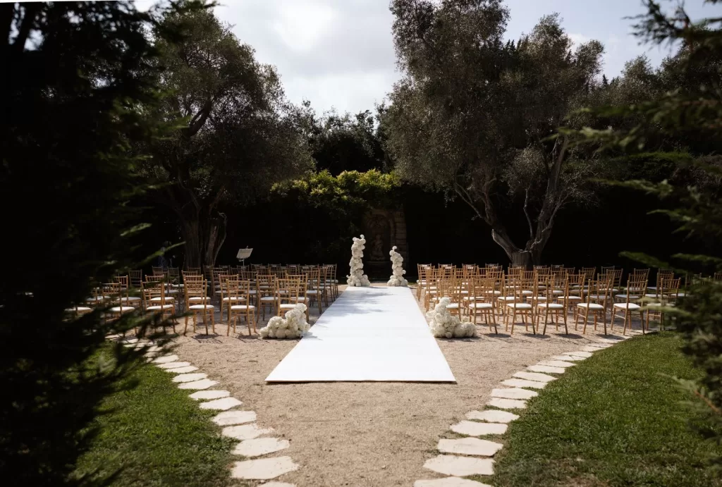 Romantic garden ceremony setup at Bastide du Roy, with white chairs and floral arrangements.