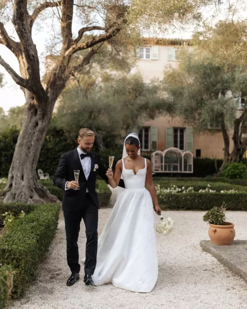 Bride and groom strolling through the lush gardens of Bastide du Roy, sharing an intimate moment.