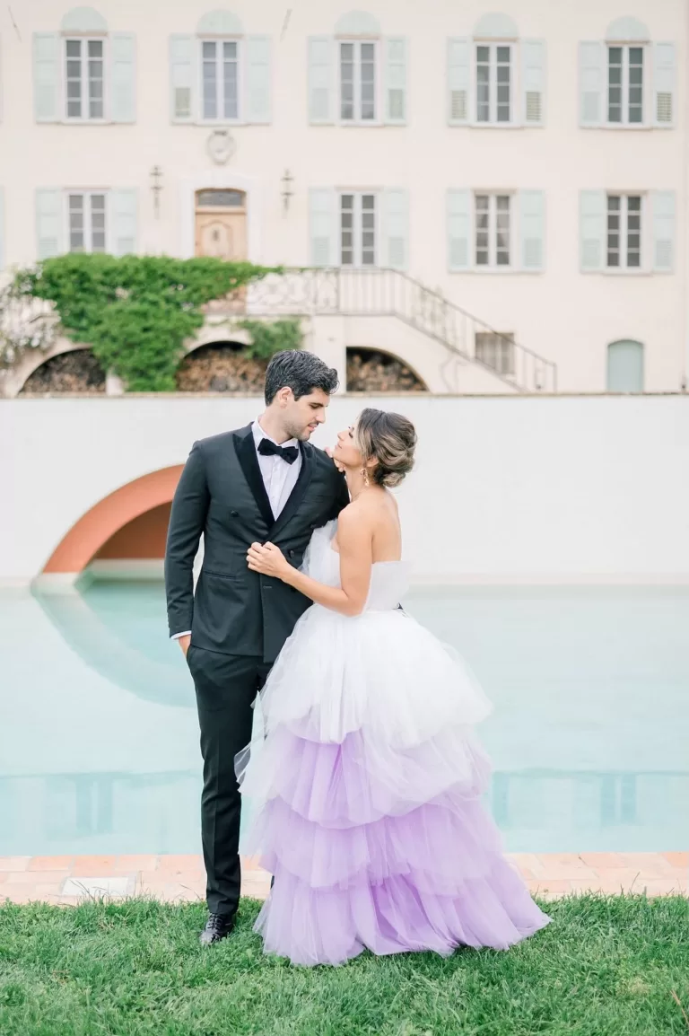 Intimate embrace of newlyweds beside the reflective pool at Bastide du Roy, with soft evening light highlighting their silhouette against the water.