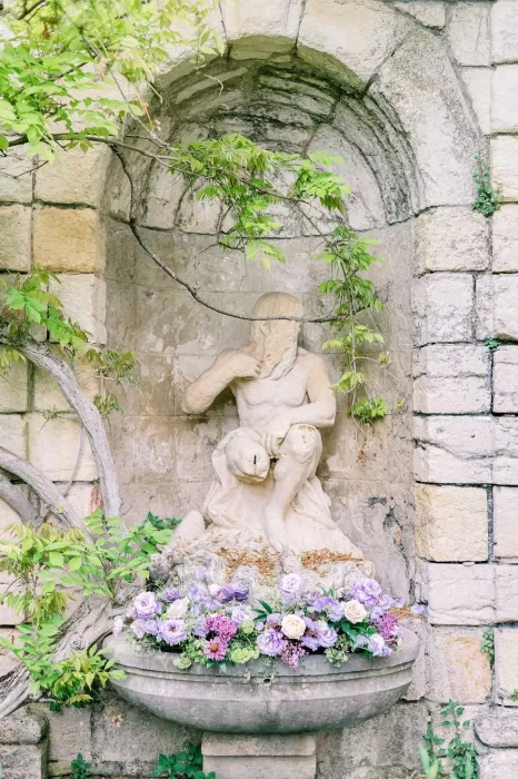 Close-up of a moss-covered garden statue nestled among lavender and olive trees in the enchanting grounds of Bastide du Roy.