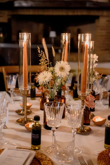 Close-up of floral and candle centerpieces at a Borgo Sant Ambrogio wedding, blending soft neutrals with amber tones and glassware.