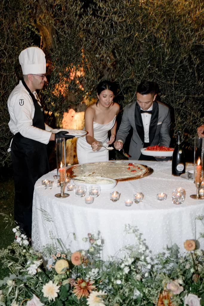 Bride and groom prepare dessert with the chef under candlelight at Borgo Sant Ambrogio