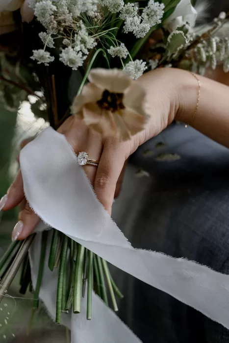 Elegant engagement ring wrapped in white ribbon among wildflowers at Borgo Sant'Ambrogio.