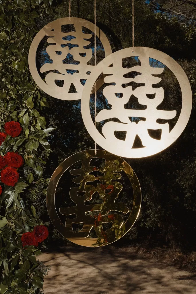 Golden double happiness symbols hanging from a floral arch during a wedding ceremony at Ca Na Xica.