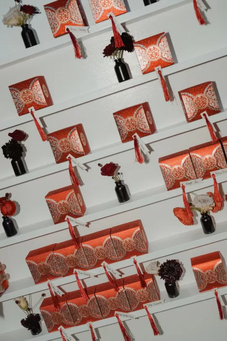 Chinese-inspired escort card wall with red tassel boxes and single stem florals at Ca Na Xica wedding.