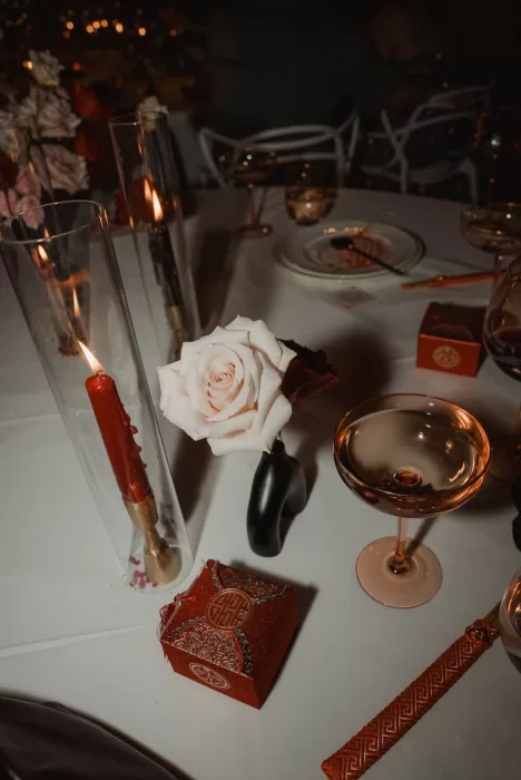Romantic evening table setting at Ca Na Xica with blush rose, candlelight, and red wedding favor box.