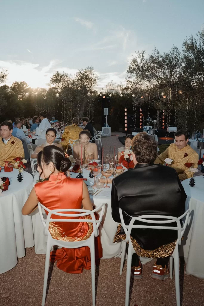 Guests gather for an outdoor wedding dinner under string lights at Ca Na Xica, surrounded by olive trees.