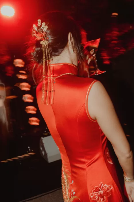 Bride sipping a martini in red cheongsam during evening celebration at Ca Na Xica
