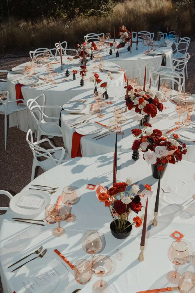 Aerial view of Ca Na Xica wedding tables with red and white flowers, gold cutlery, and rose-colored glassware.