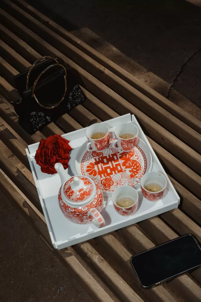 Traditional tea ceremony tray with red porcelain teaware and a red rose resting on a wooden bench at Ca Na Xica.