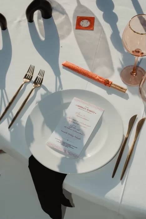Wedding menu card on plate with chopsticks and gold cutlery at Ca Na Xica outdoor reception