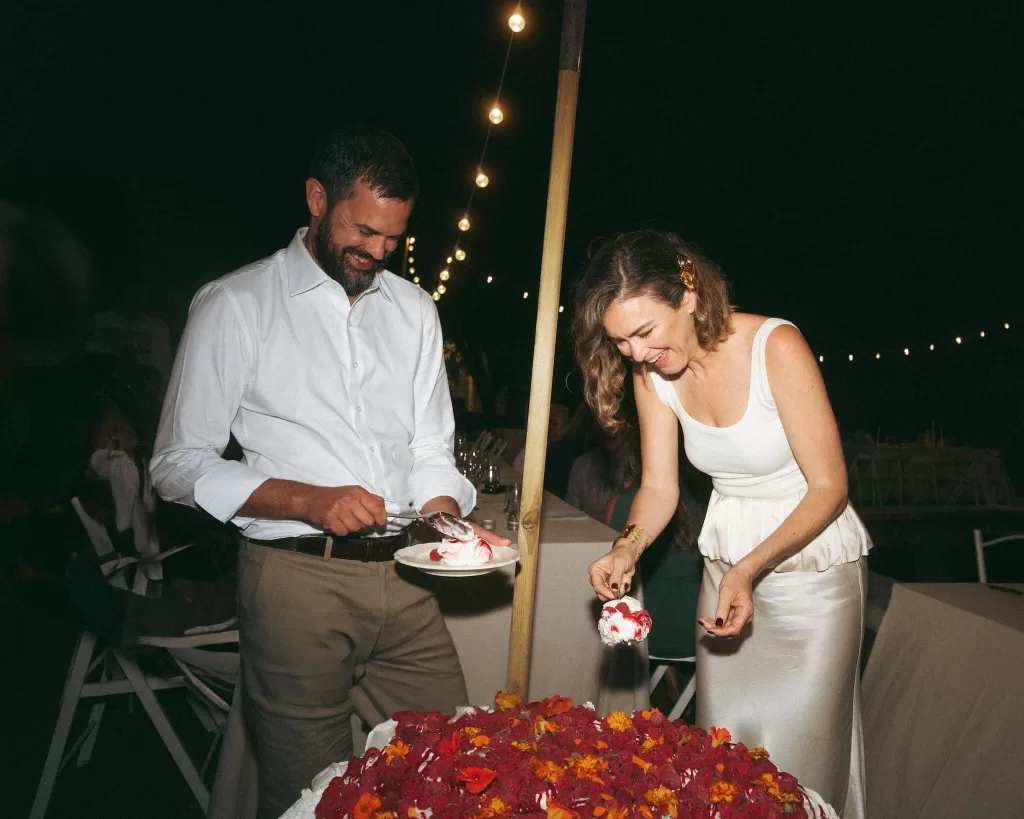 Bride and groom cutting their wedding cake under twinkle lights at Casa Sacoto