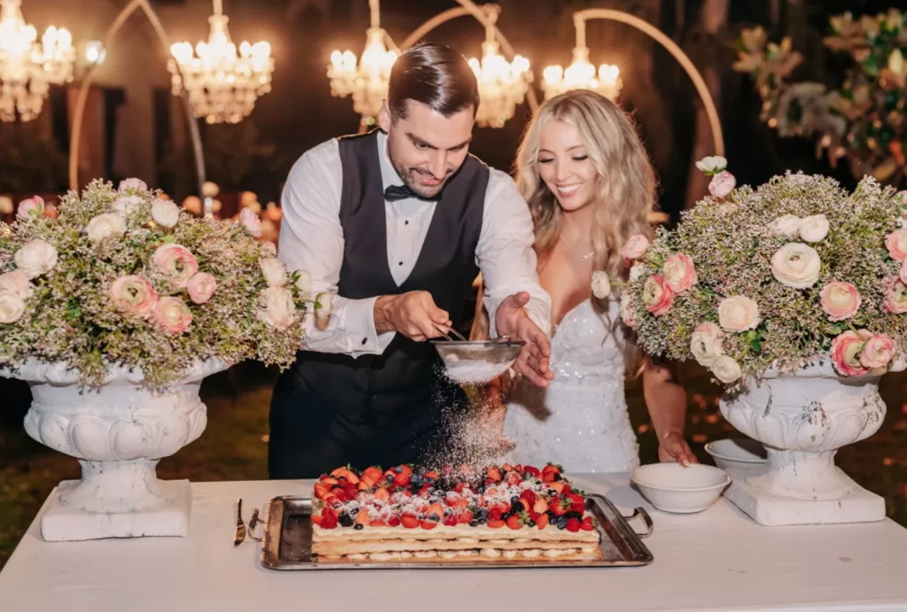 Bride and groom cutting a rustic wedding cake under fairy lights at Villa Ravano