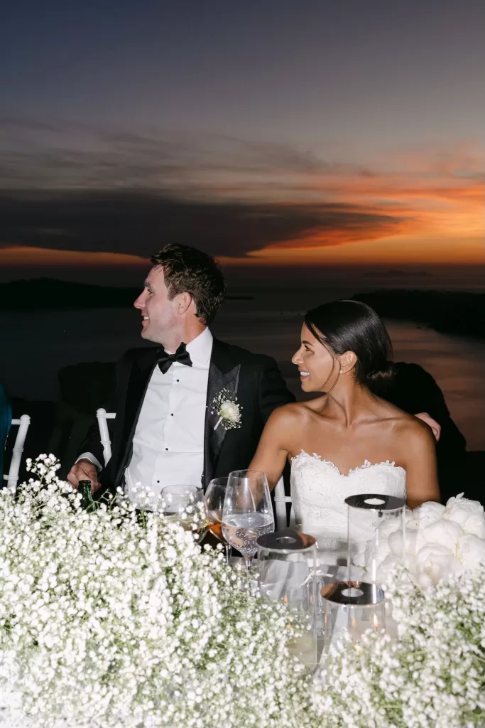 Guests raise glasses in a sunset toast during an outdoor wedding dinner at Rocabella Santorini
