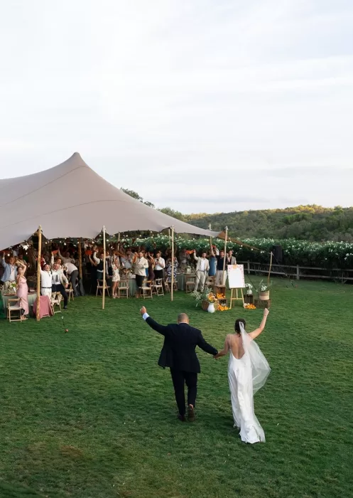 Just-married couple entering the reception tent at Mas Torroella to cheers and applause from guests.